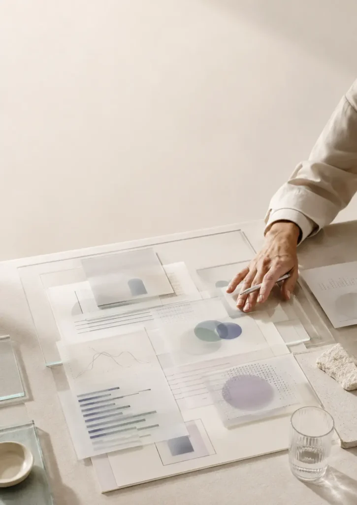 Mesa clara con capas translúcidas, gráficos abstractos y una mano adulta revisando la decisión final, como metáfora de IA como apoyo y responsabilidad humana en ciberseguridad.